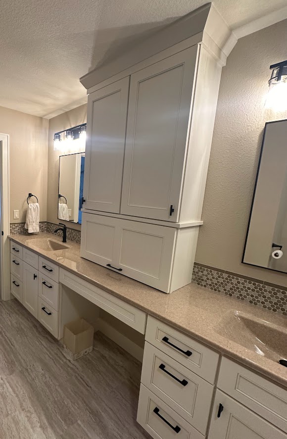 Bathroom remodel showing two sink spaces on a long countertop. Between the sinks is a large cabinet set on top of the quartz countertop.