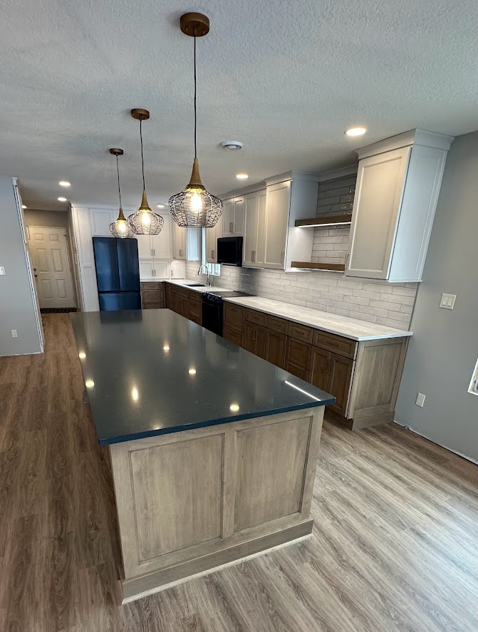 Kitchen remodel with light floor cabinets and white wall cabinets. There are some floating shelves with lighting lining the bottom of them.