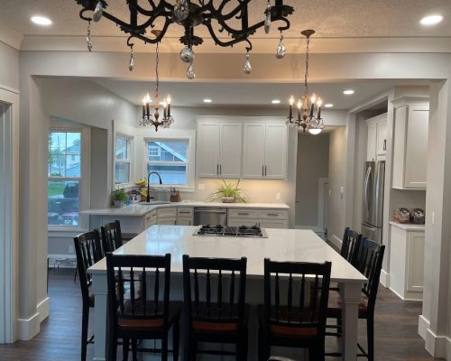 Kitchen remodel showing a kitchen island with seating space for 7 chairs and the oven built in to one side.