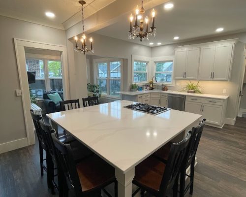 Kitchen remodel showing a kitchen island with seating space for 7 chairs and the oven built in to one side.