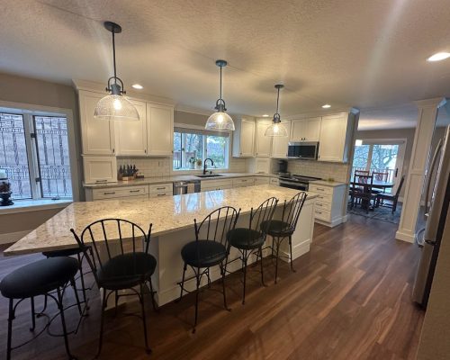 Kitchen remodel with new white cabinets and a kitchen island with barstool seating space.